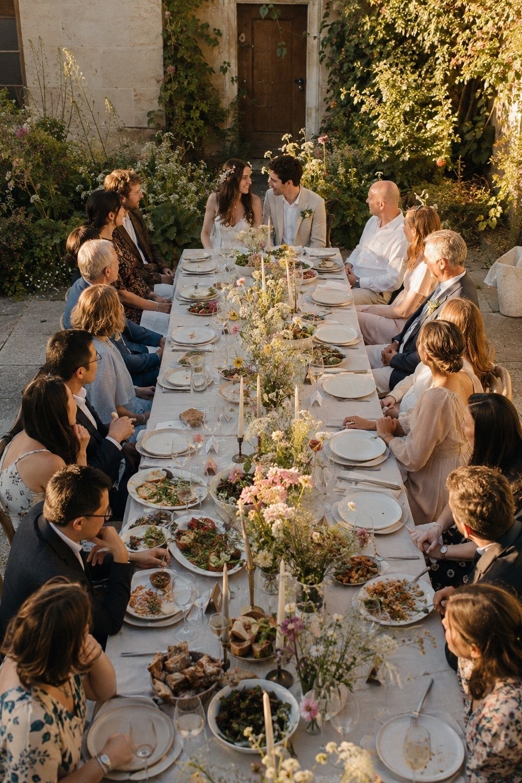 Newlyweds seated in the middle of a long-table family reception meal