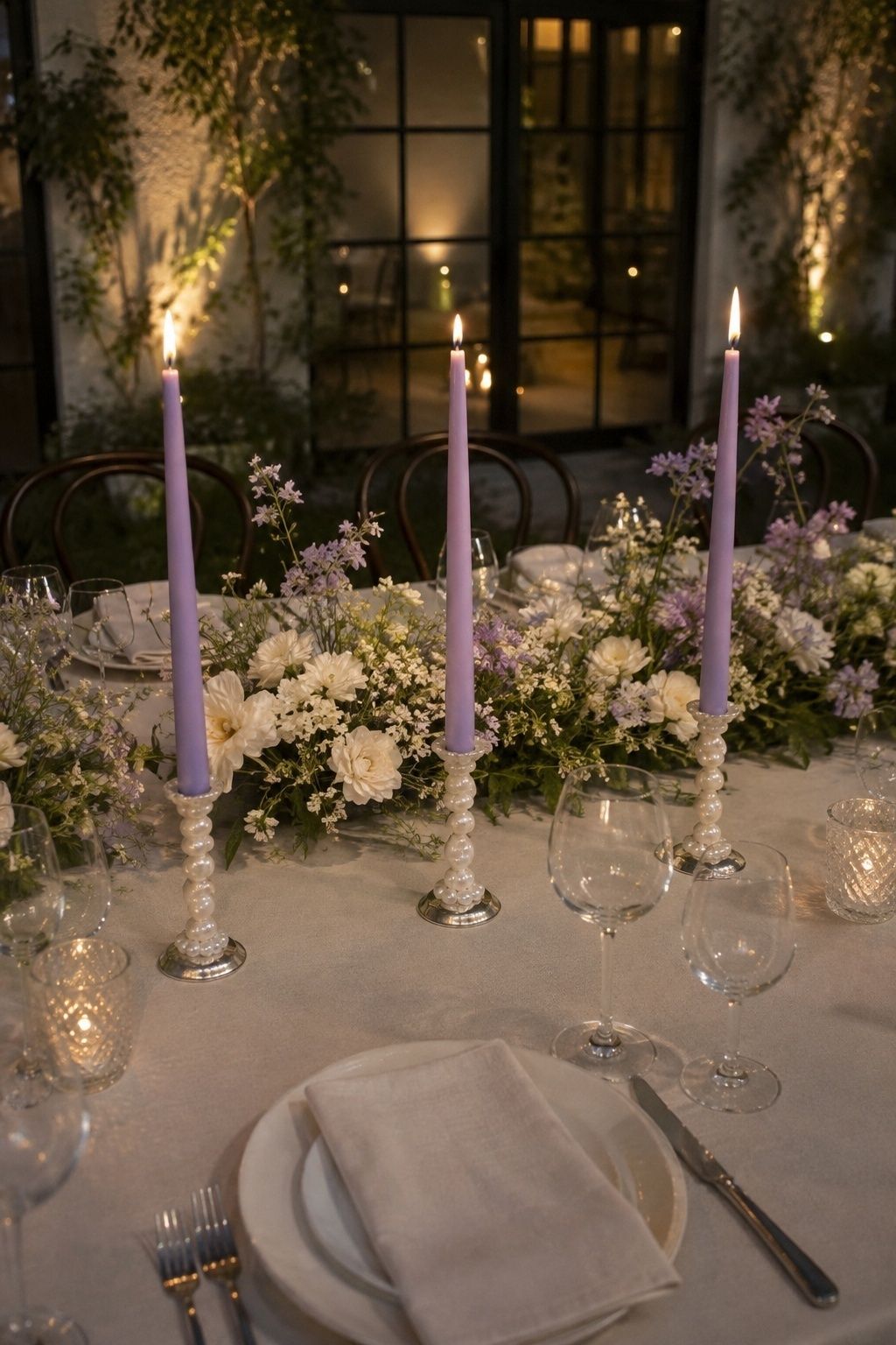 Lavender taper candles in pearl holders on an intimate wedding table