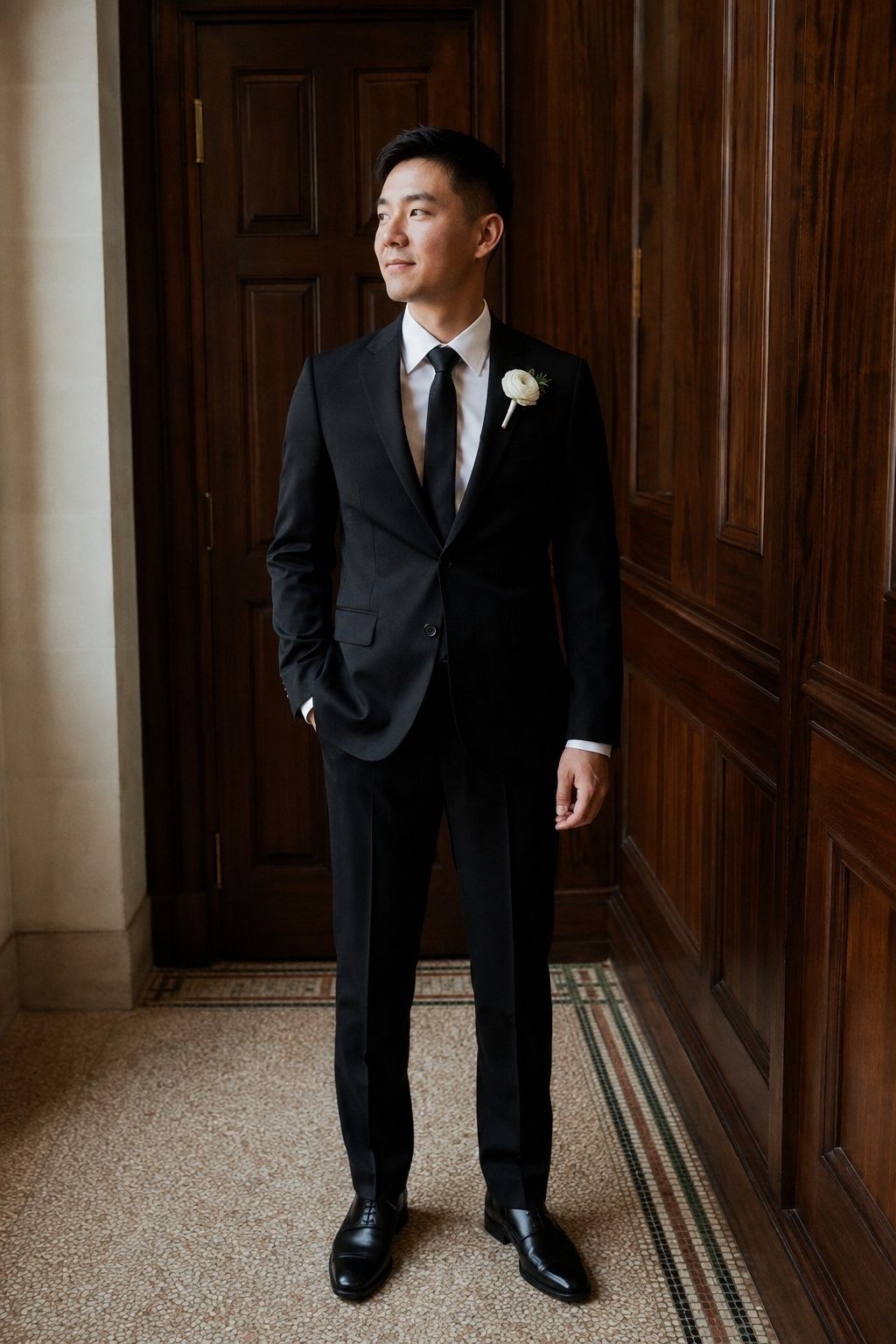 Groom in black tailoring with a slim tie and a small white boutonniere