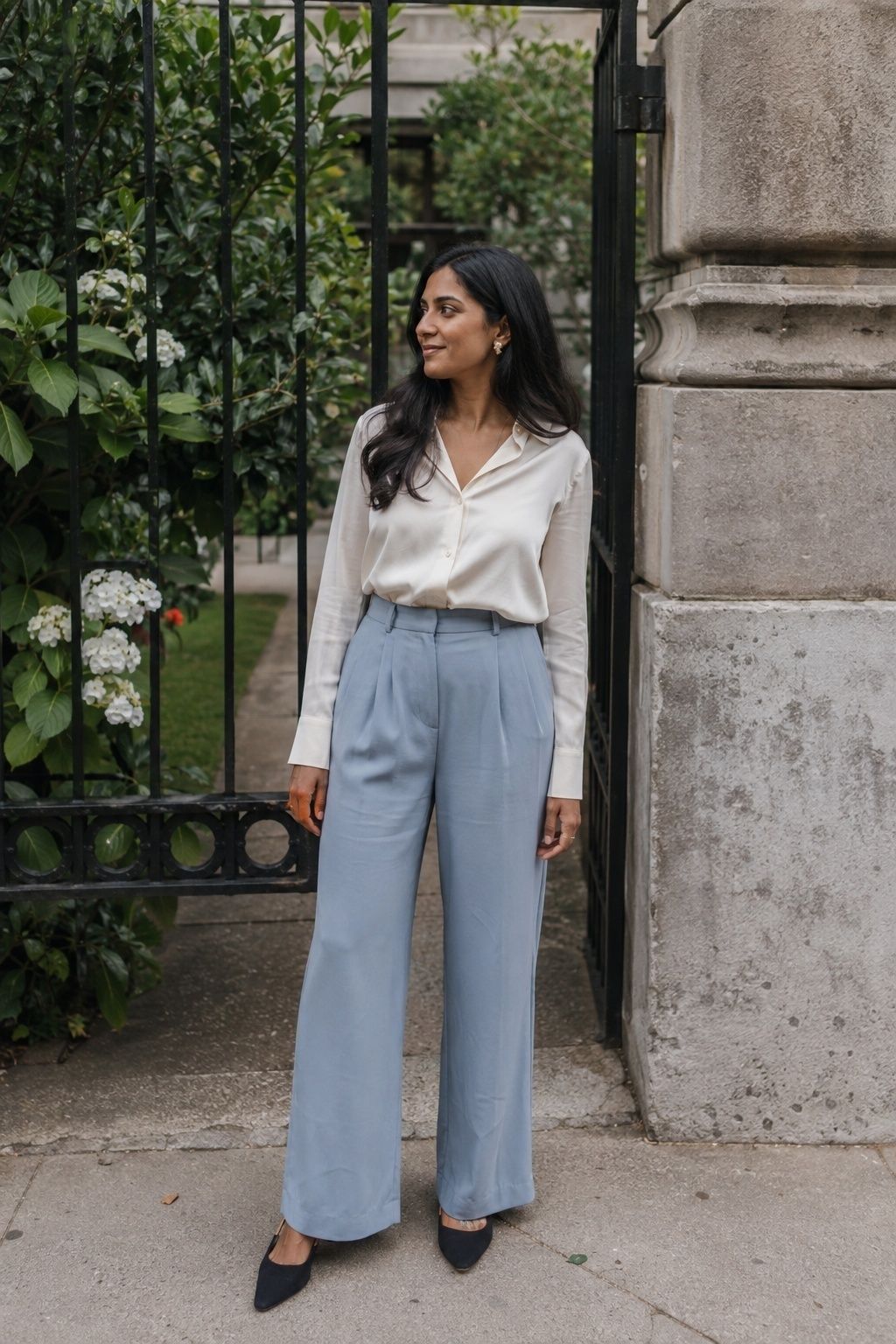 Wedding guest in blue tailored trousers, an ivory blouse and dark flats