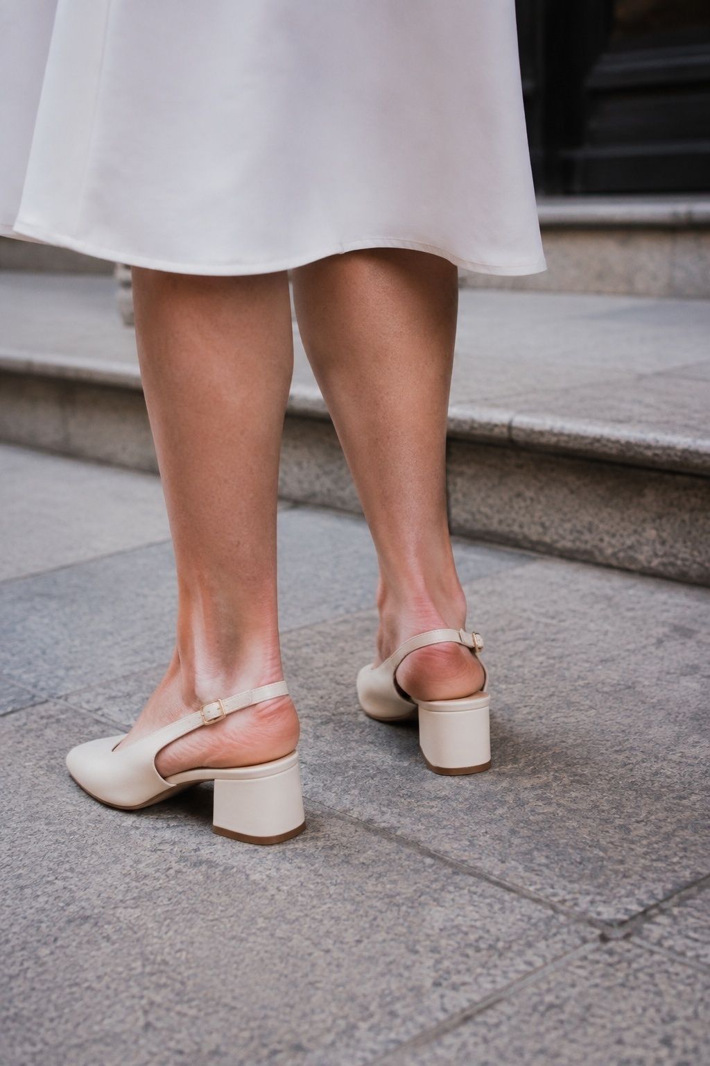 Cream block heel slingbacks worn on paving beside registry office steps