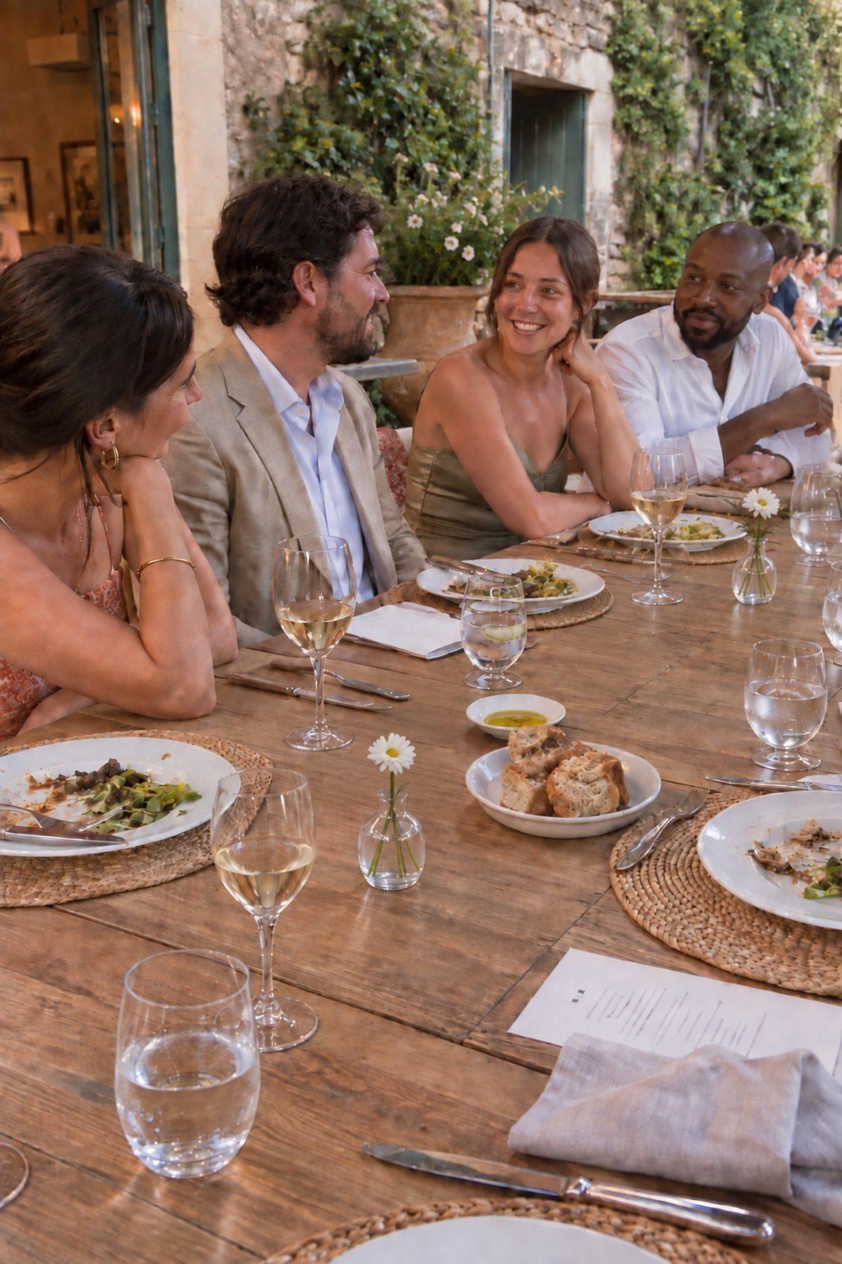 Guests talk across a low airy floral runner with generous table gaps.