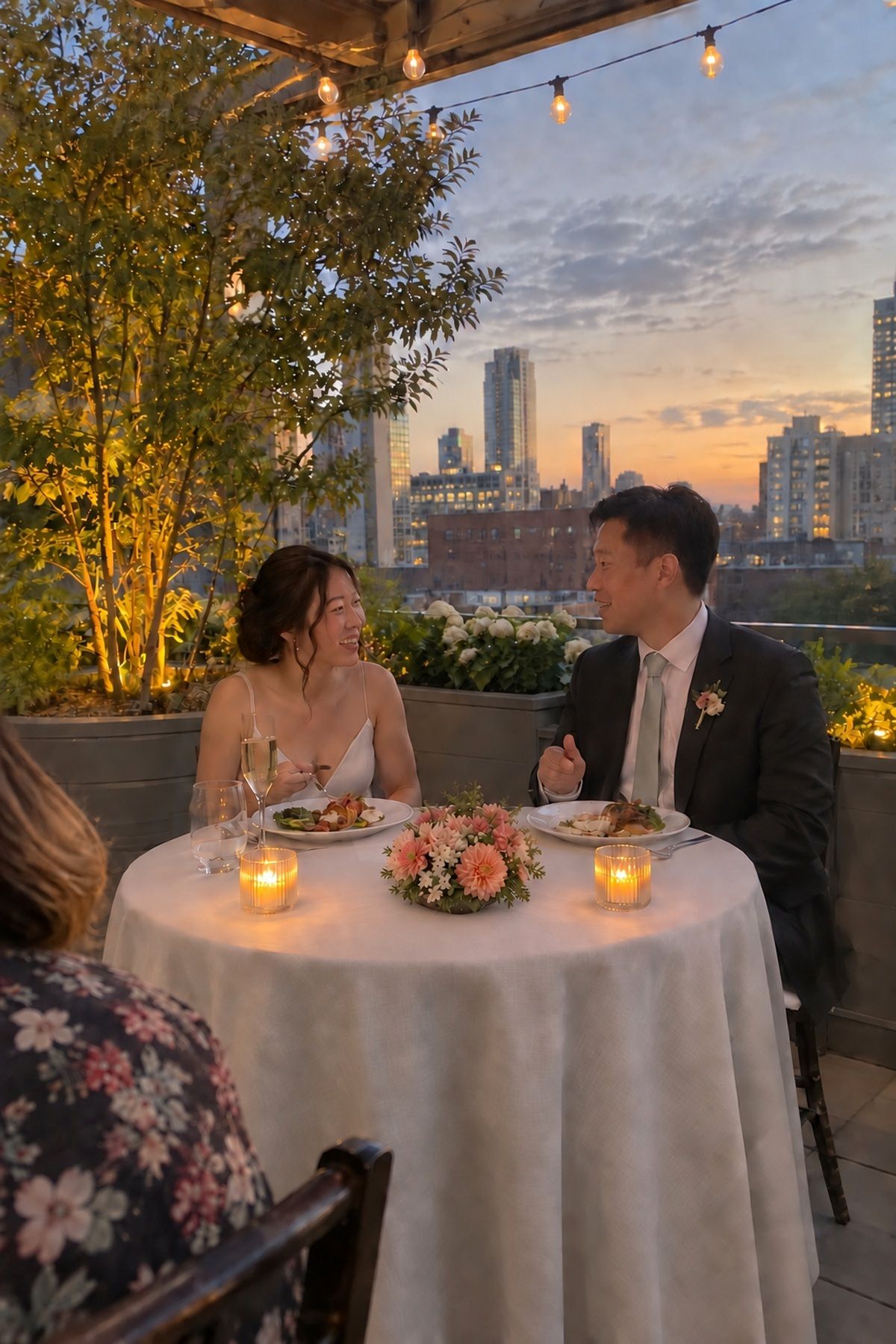 An East Asian couple talks at a glowing but uncluttered summer sweetheart table.