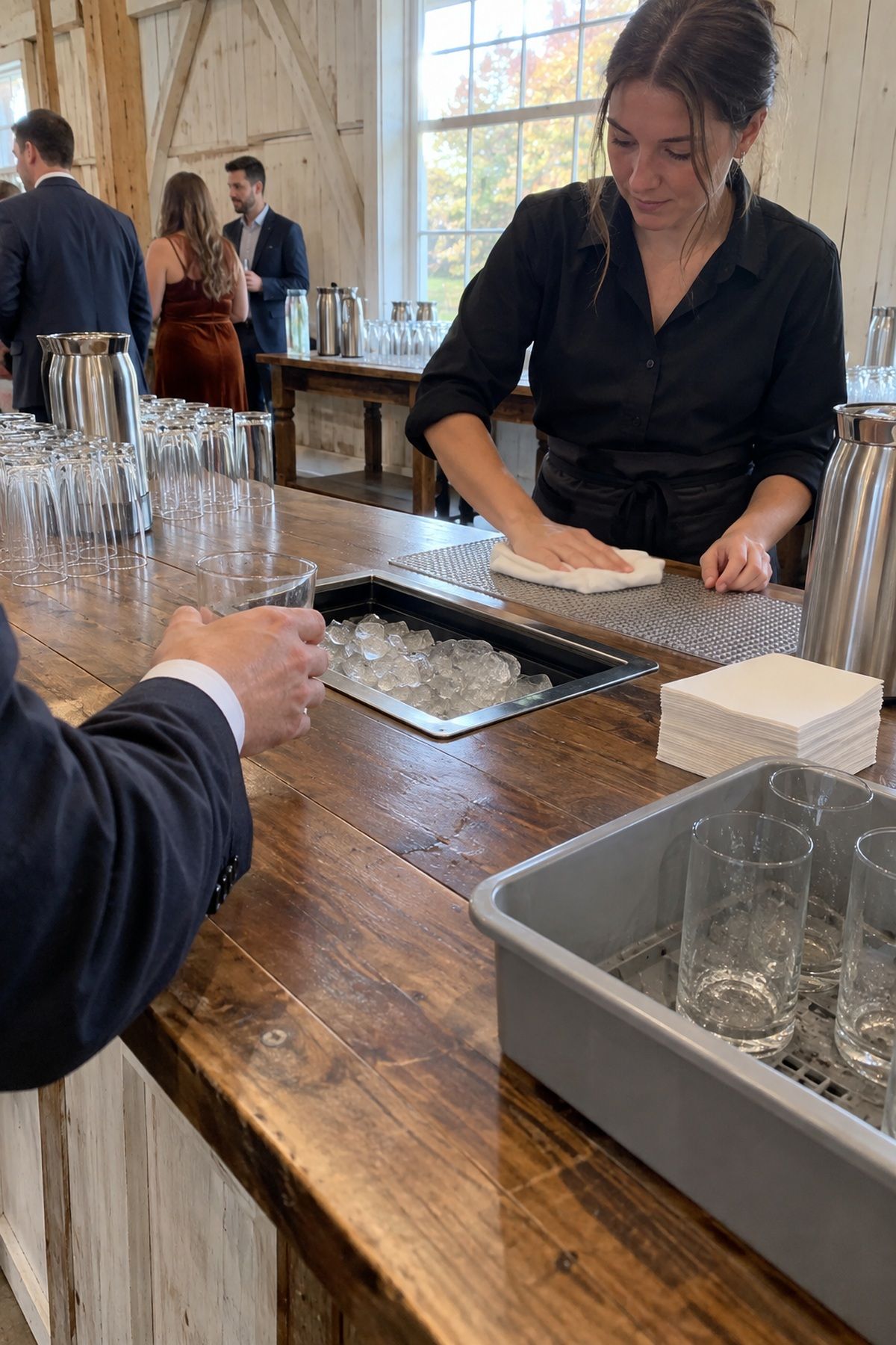 An uncluttered farmhouse-table bar leaves clear space for ice, glassware, returns, and service.