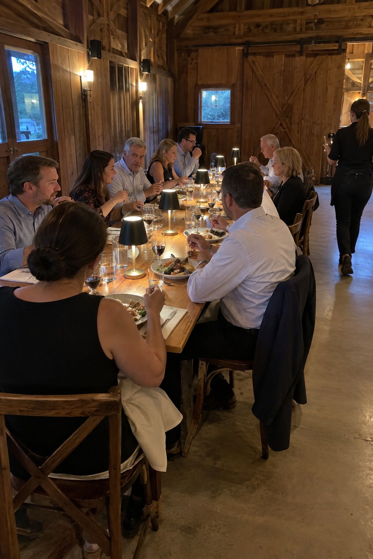 Guests share dinner at one long table during an intimate September wedding reception.