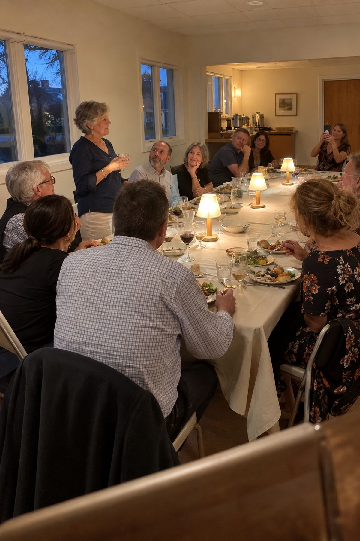 An older guest toasts at a flower-free September wedding dinner table.