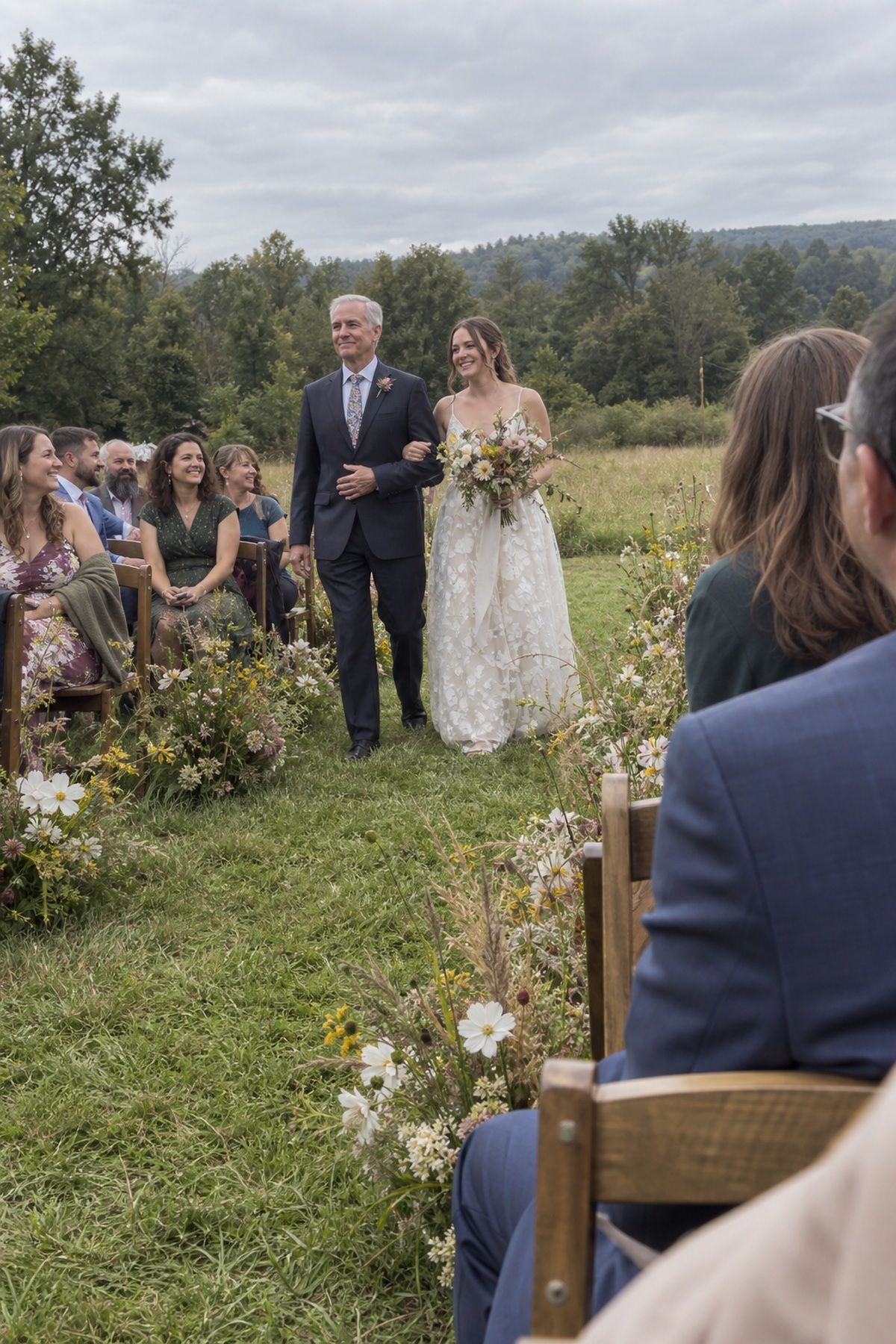 A bride walks through a late-season wildflower meadow ceremony with an older relative.