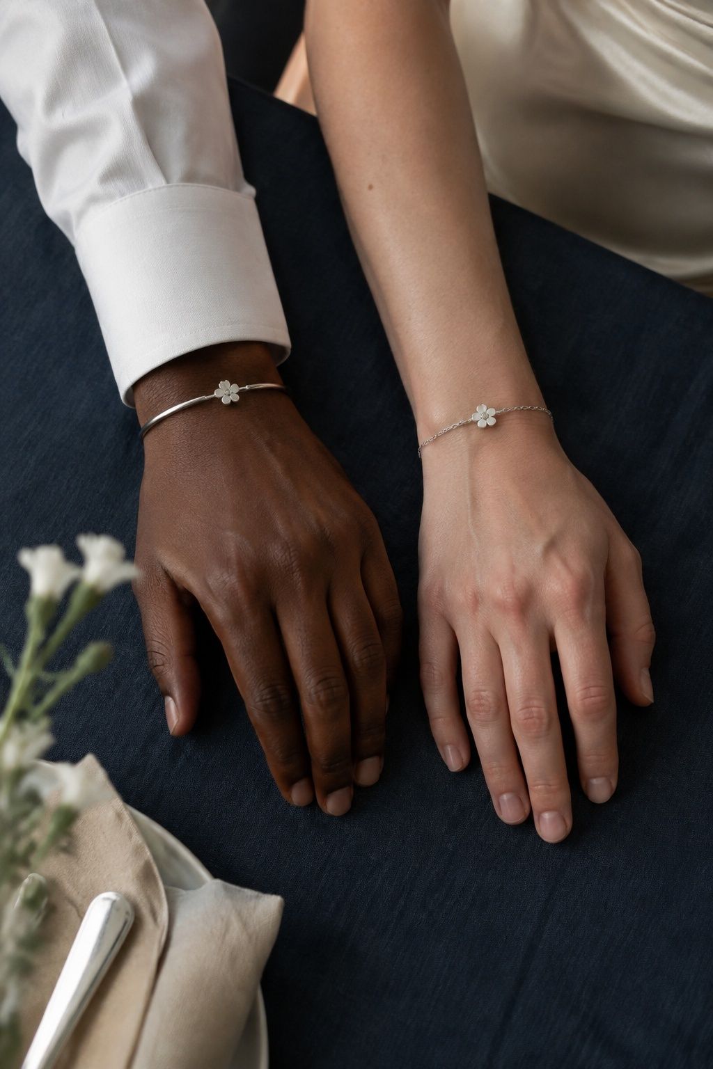 Both partners wearing matching silver flower bracelets