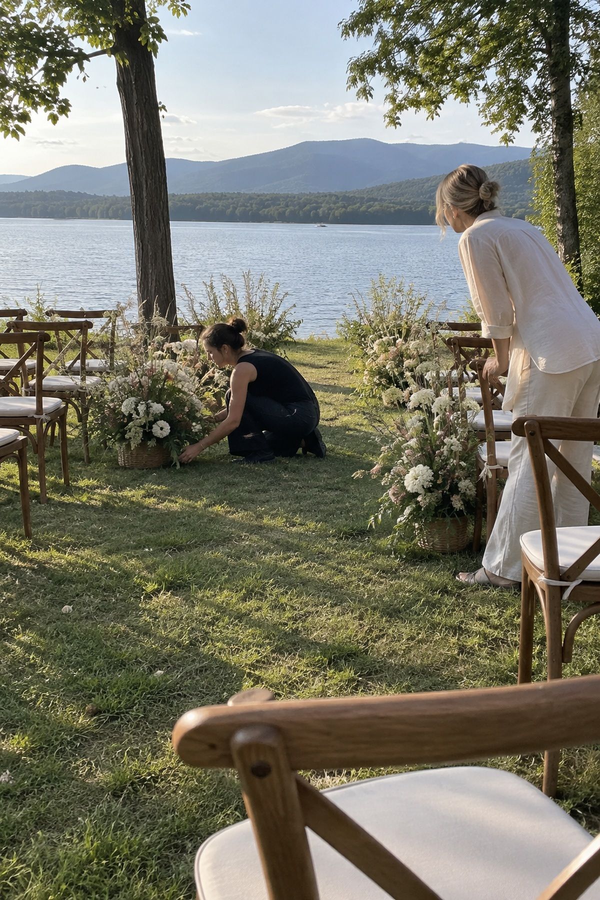 Helpers adjust low ceremony flowers to keep the aisle and lake view open.