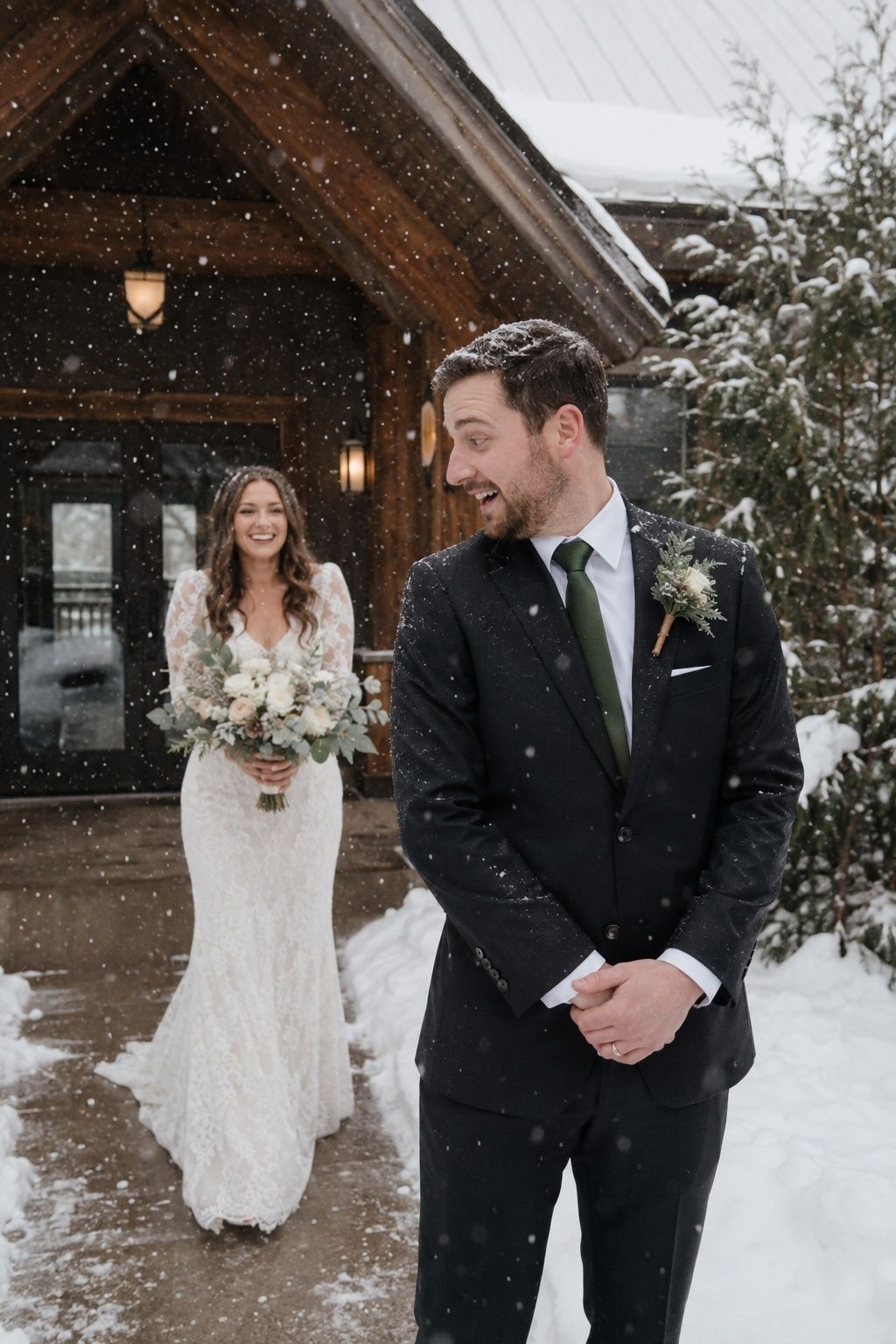 Bride and groom sharing a first look in falling snow by a lodge entrance