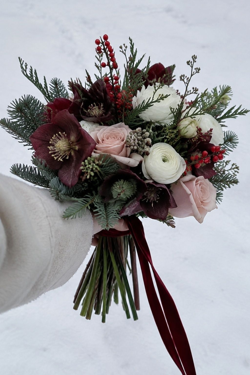 Burgundy blush and white winter wedding bouquet against clean snow