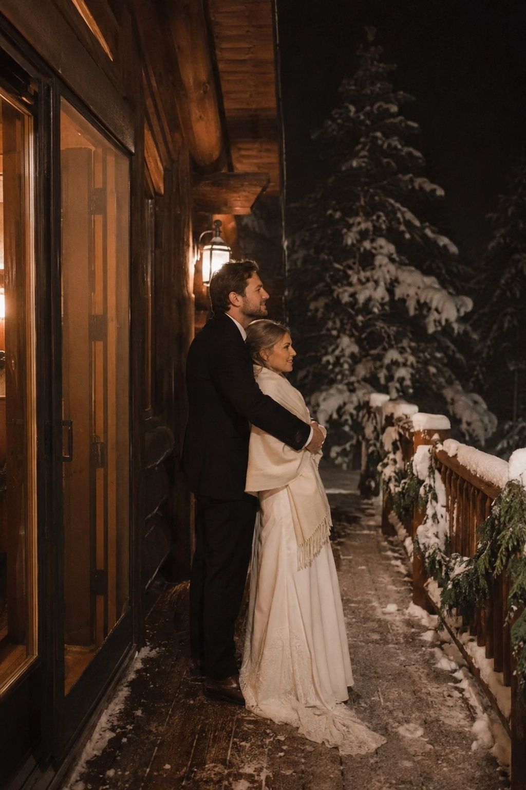 Newlywed couple sharing a quiet last snowy portrait by a warm lodge doorway