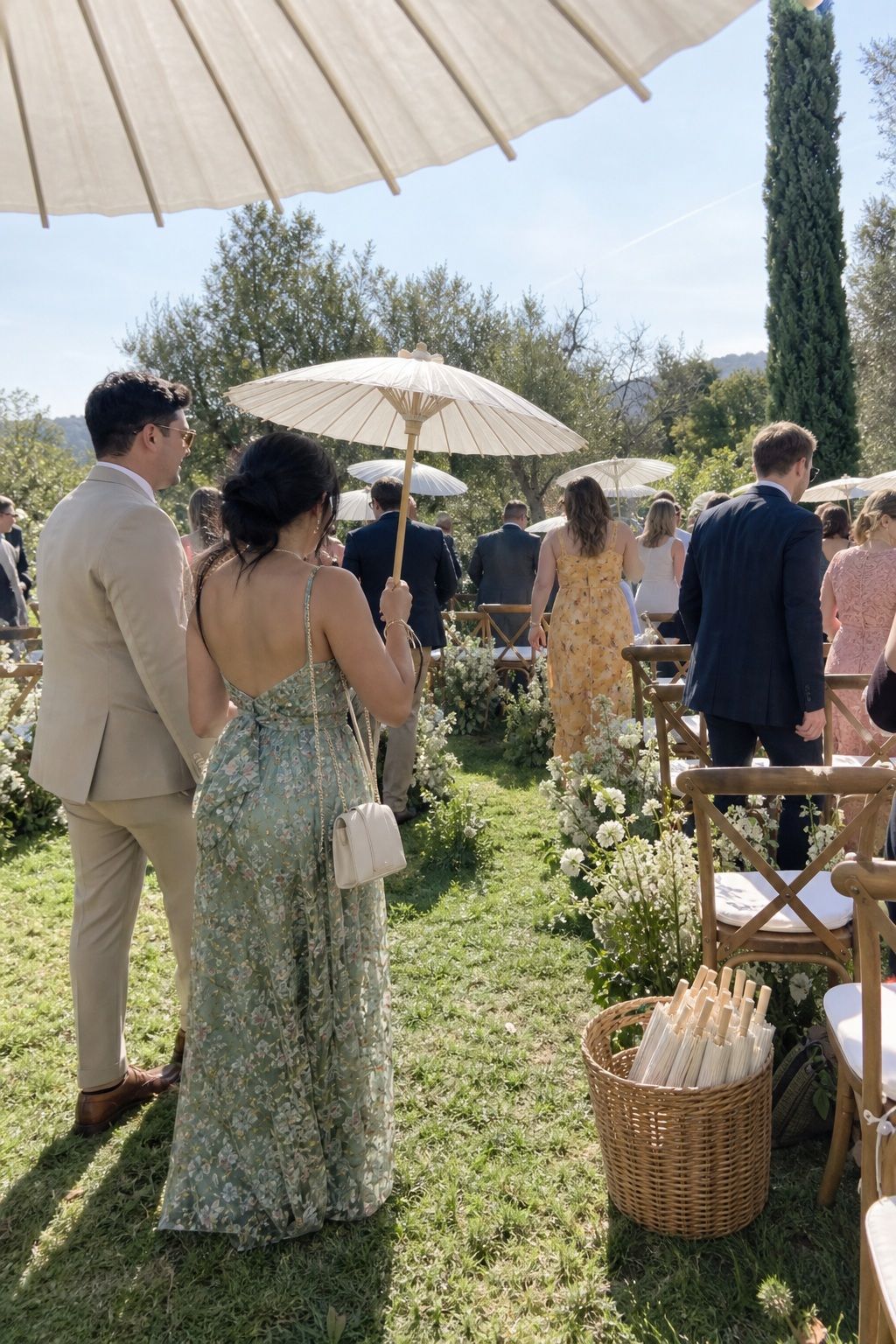 Wedding guests using ivory garden parasols beside open lawn ceremony seating