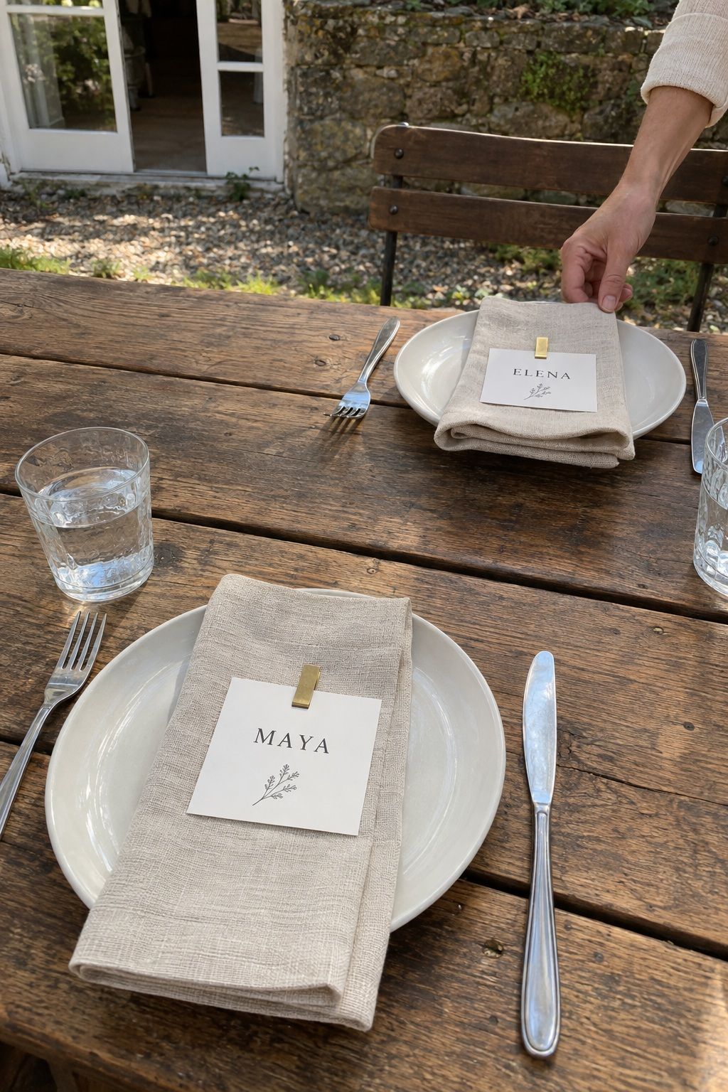 Botanical menu cards secured beneath sage napkins at an occupied garden table