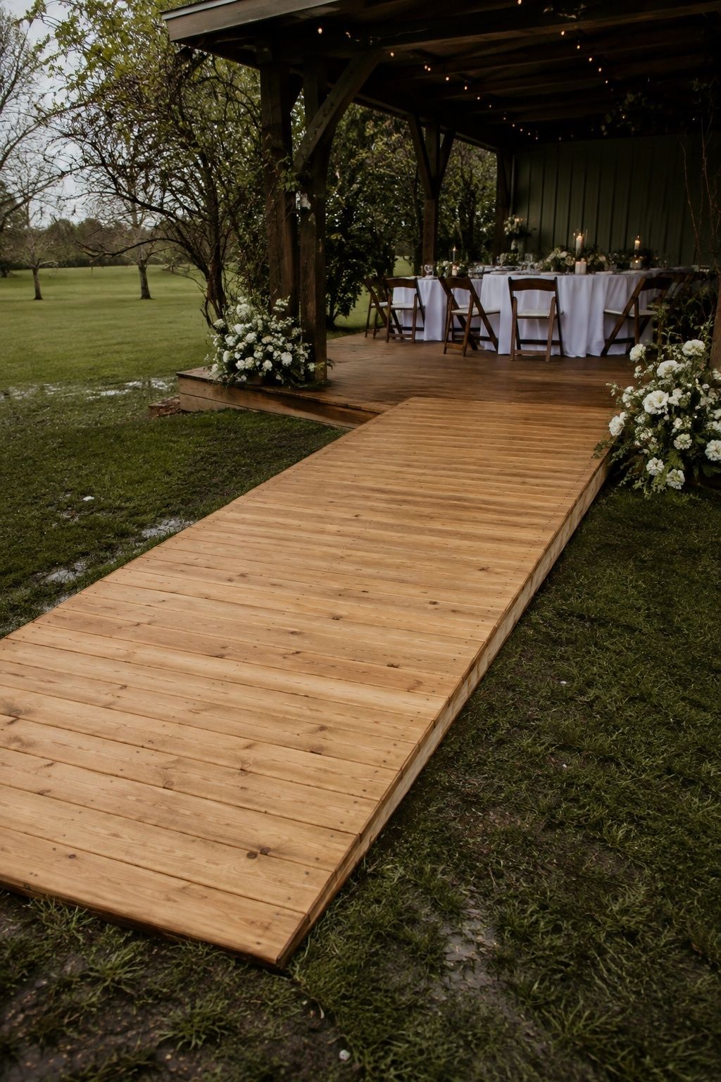 Dry timber walkway over damp grass leading into a covered wedding dining area
