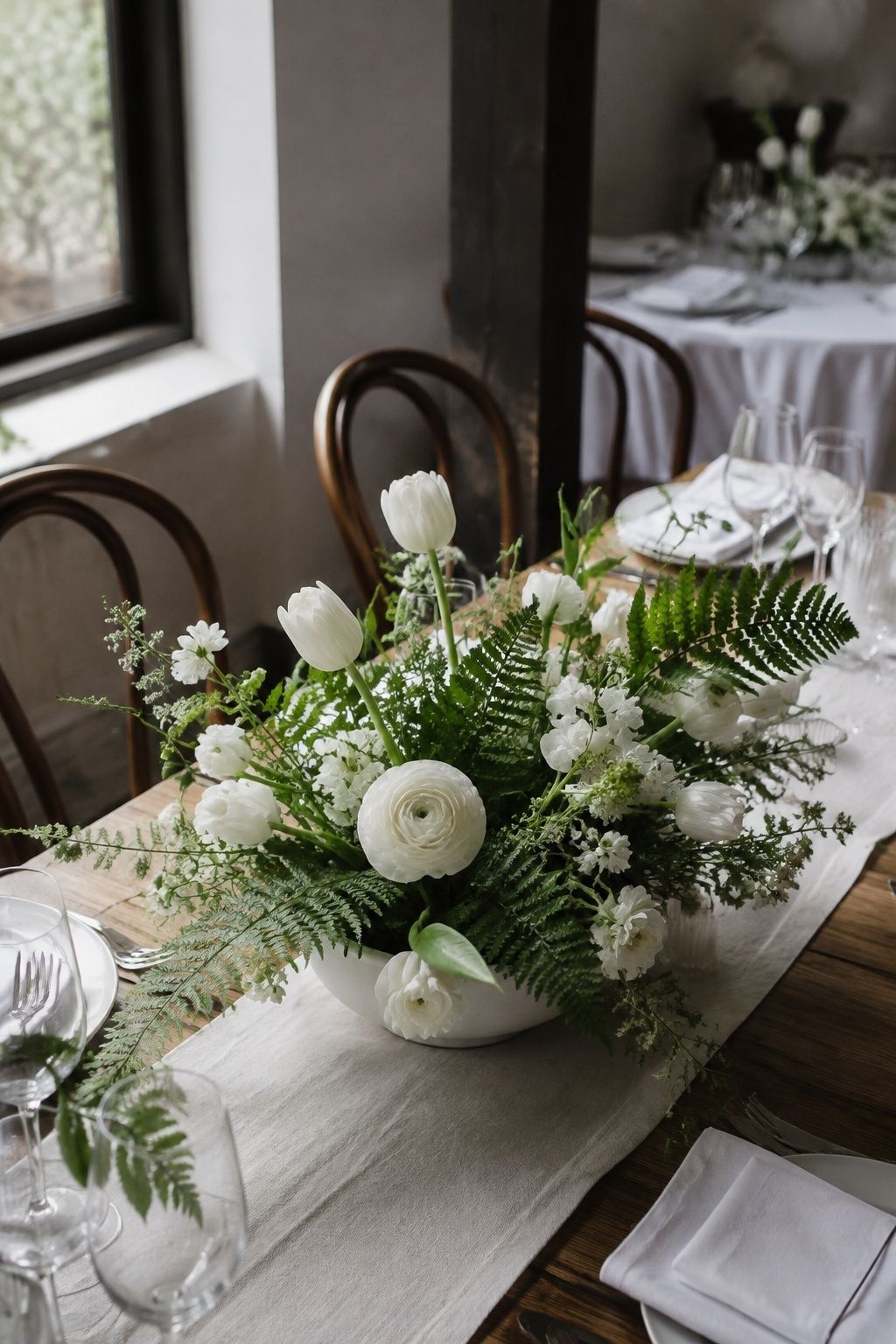 Window-lit diagonal close shot of a low white bowl with airy white ranunculus