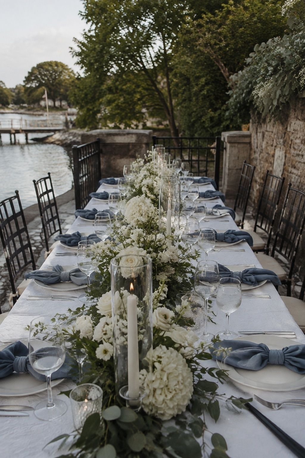 Dusty blue napkins and white flowers on a waterfront wedding table