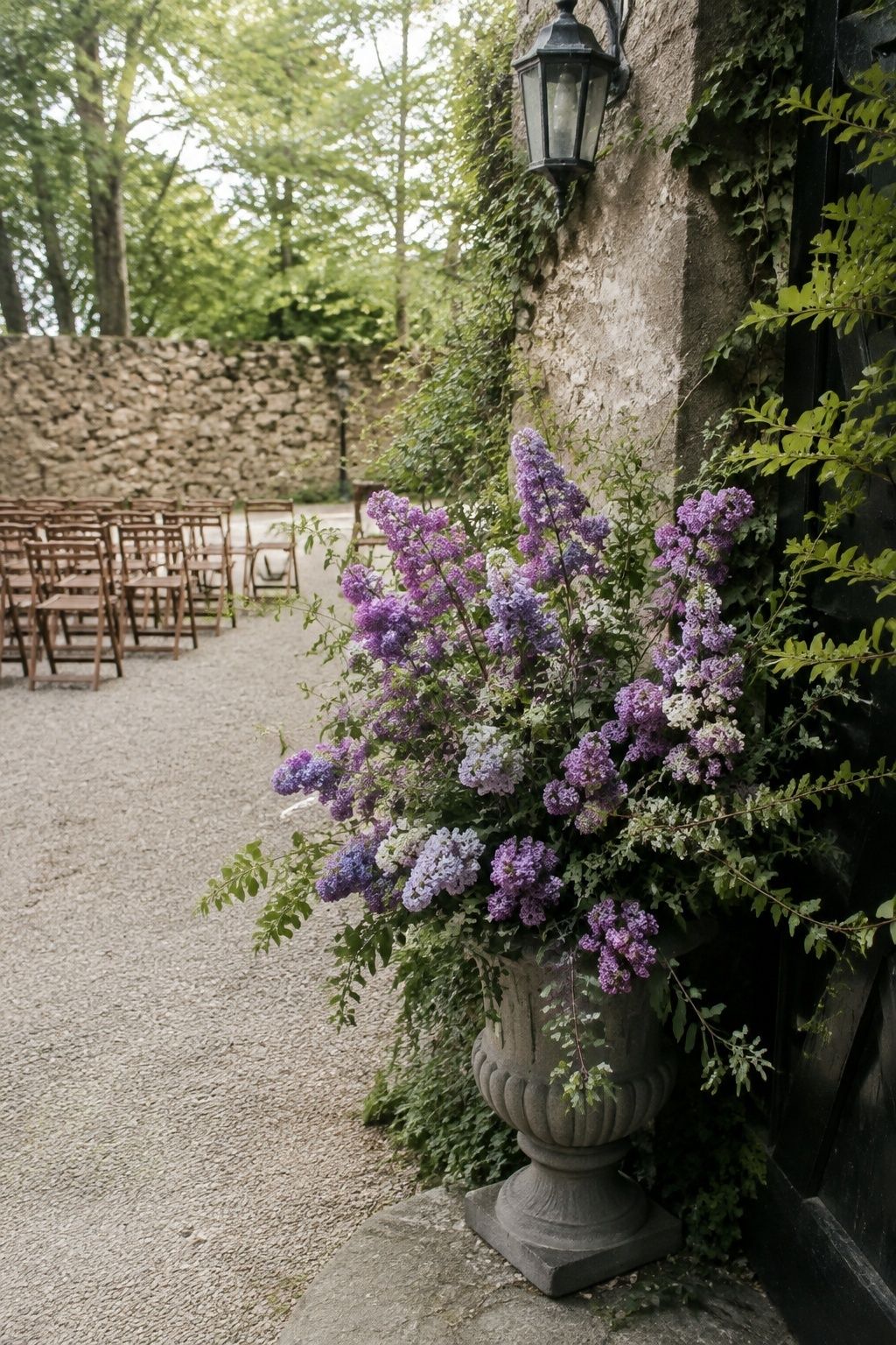 Purple lilac urn arrangement beside a garden wedding ceremony entrance.