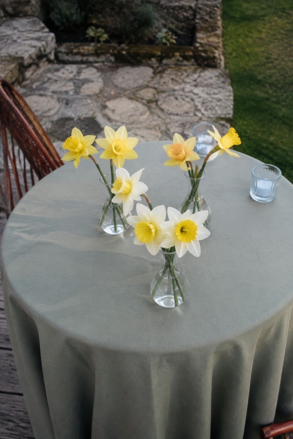Yellow and cream daffodils in three small wedding bud vases.