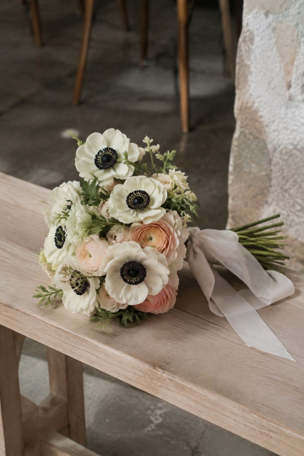 White anemones with dark centers and blush ranunculus in a bridal bouquet.