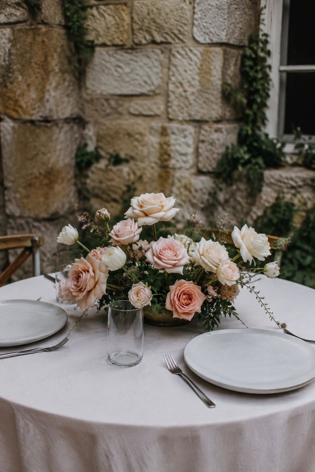 Blush garden rose centerpiece with white tulips on a small reception table.