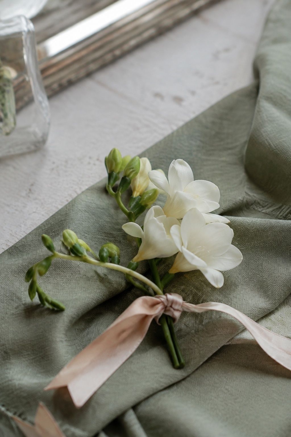 White freesia personal flowers tied with blush ribbon.
