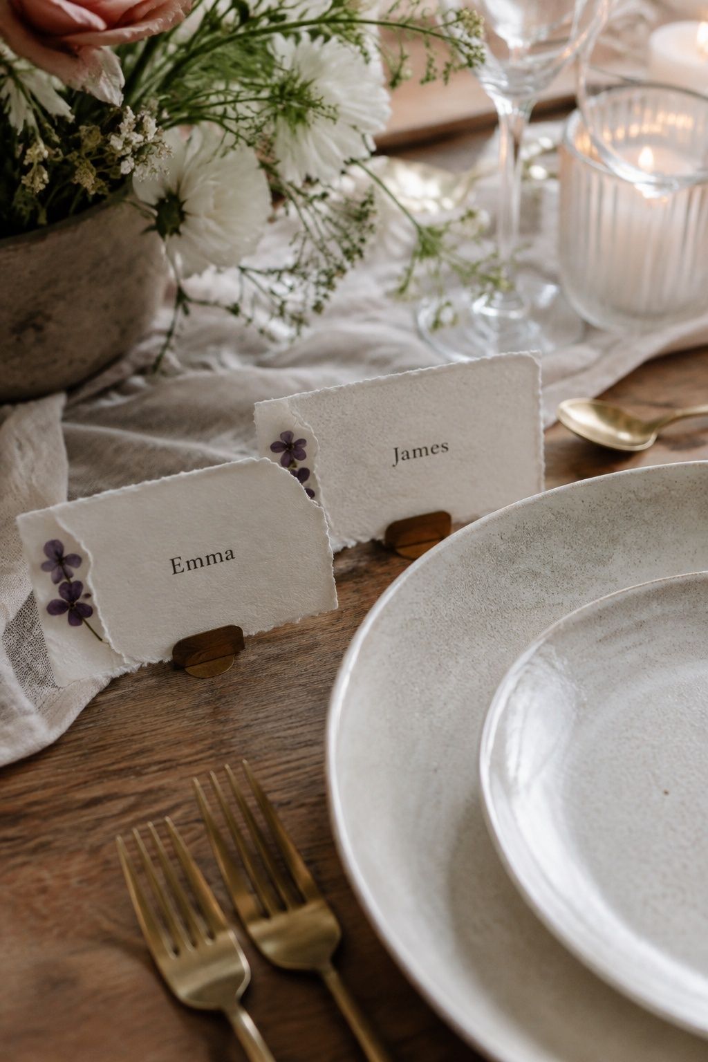 Pressed-violet place cards beside ceramic wedding plates