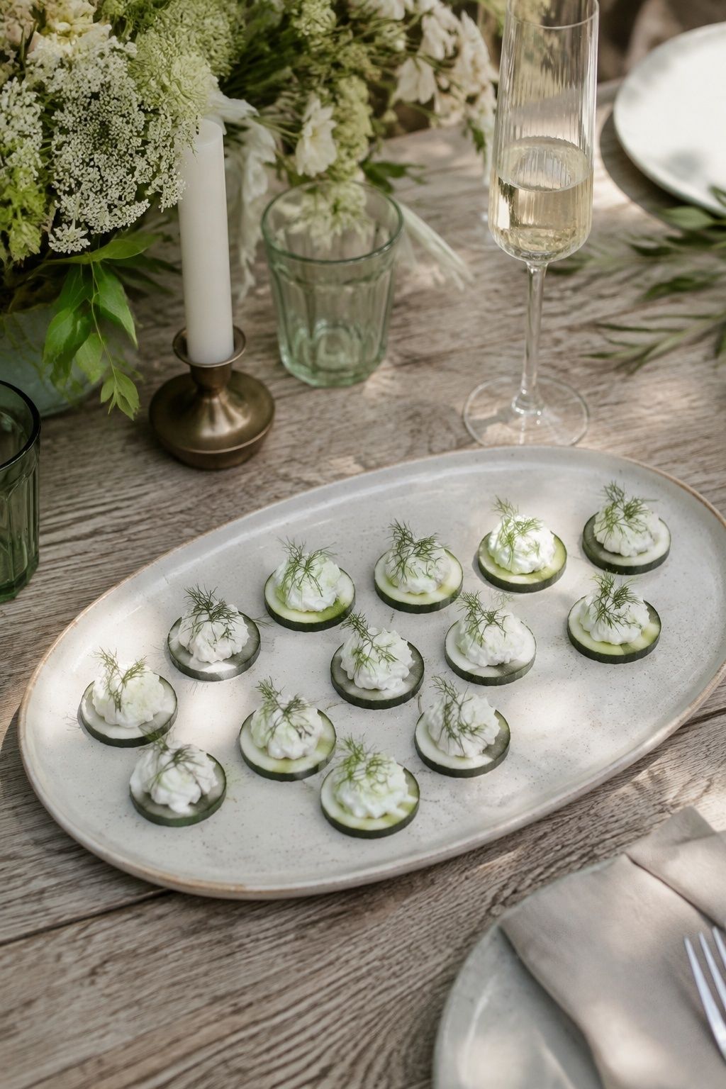 Small cucumber rounds topped with whipped feta and dill on an oval ceramic tray at an intimate wedding