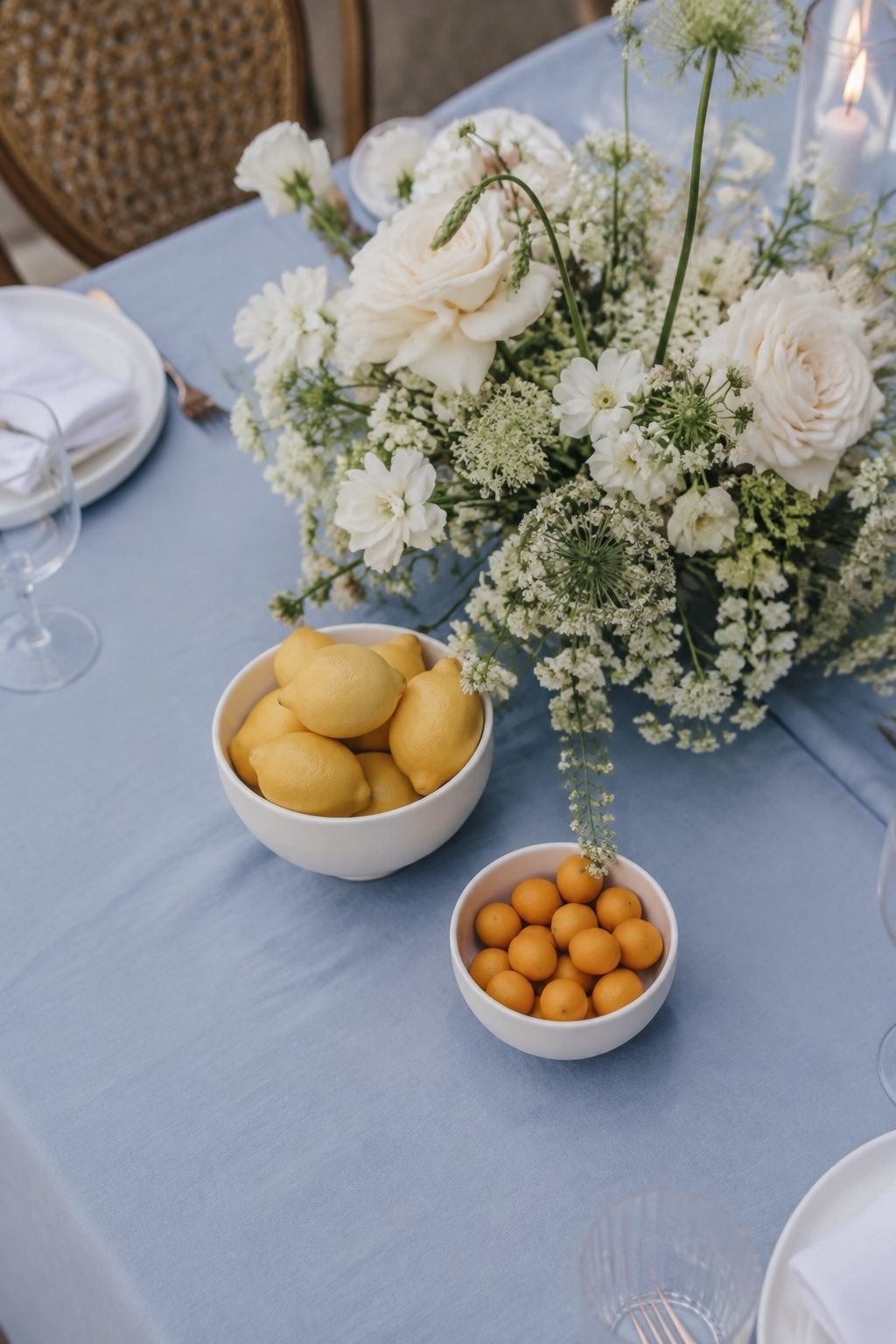 Lemons and kumquats beside white flowers on blue linen