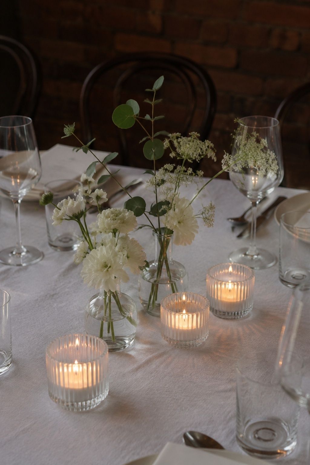 Three ribbed glass votives beside low wedding flowers