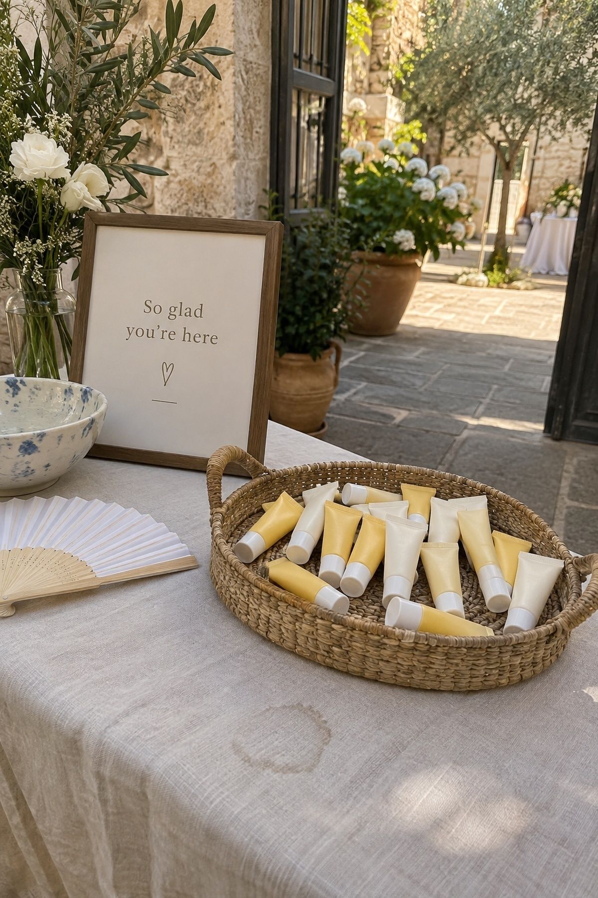 Mini sunscreen bottles in a woven tray on a summer wedding welcome table.