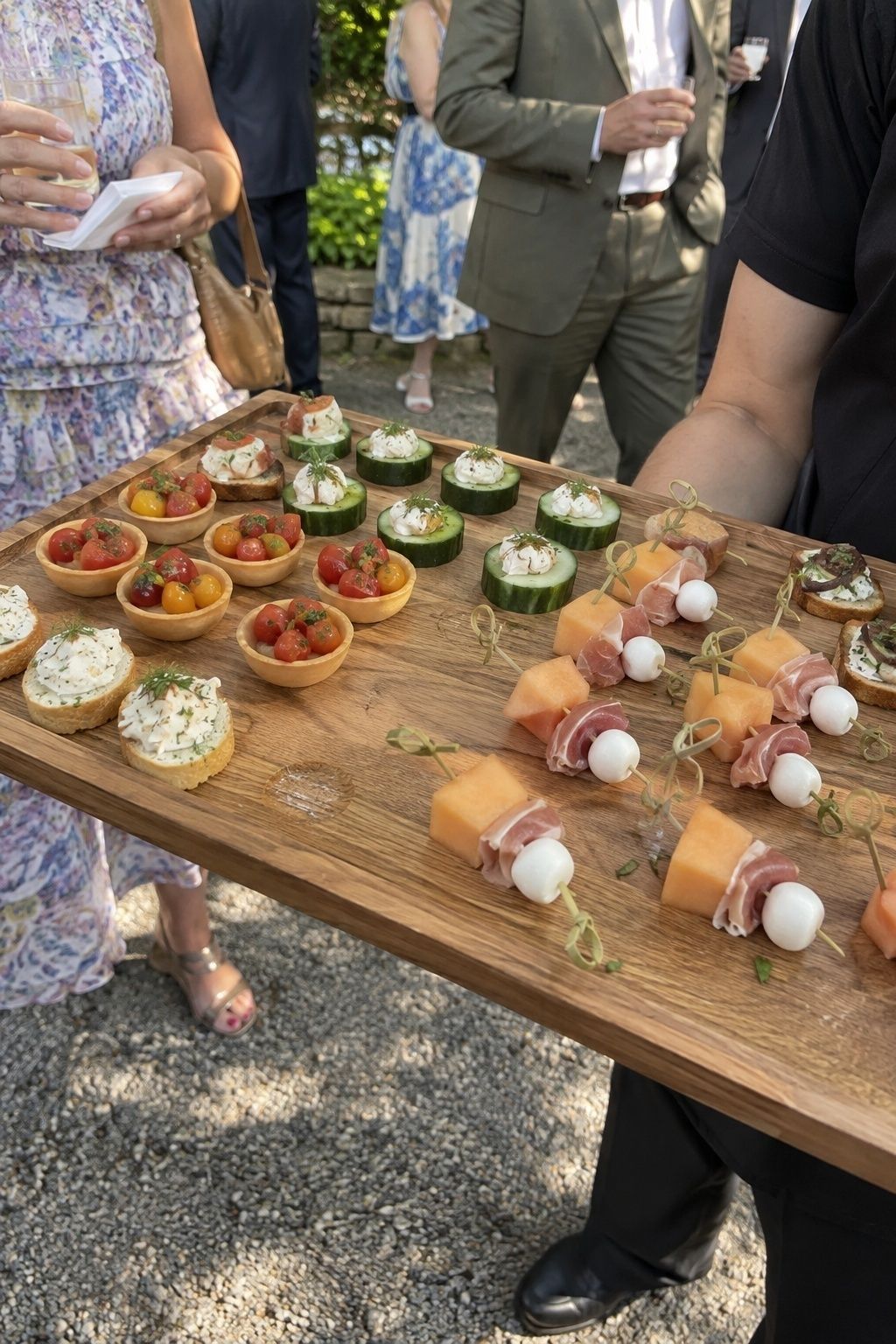 Passed tray of chilled summer wedding appetizers moving through an outdoor cocktail hour