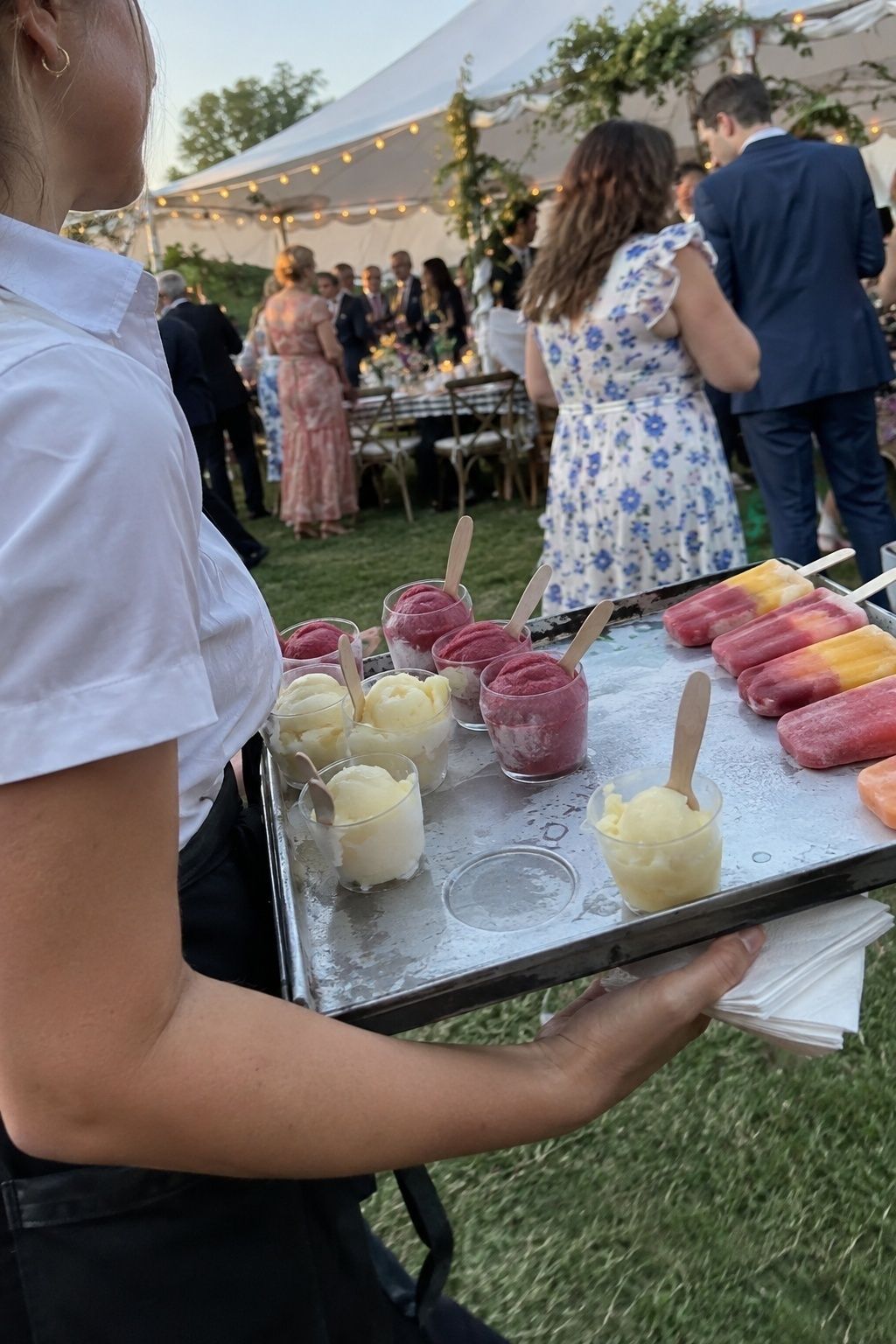 Server carrying sorbet cups and mini fruit popsicles at a summer wedding