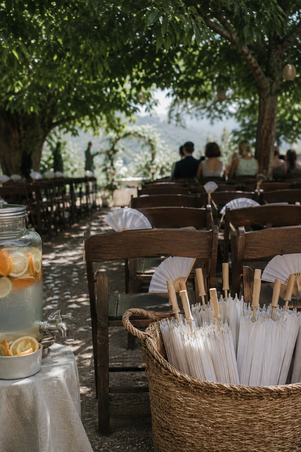 Summer wedding heat and shade plan with paper fans, parasols, citrus water, and shaded ceremony seating
