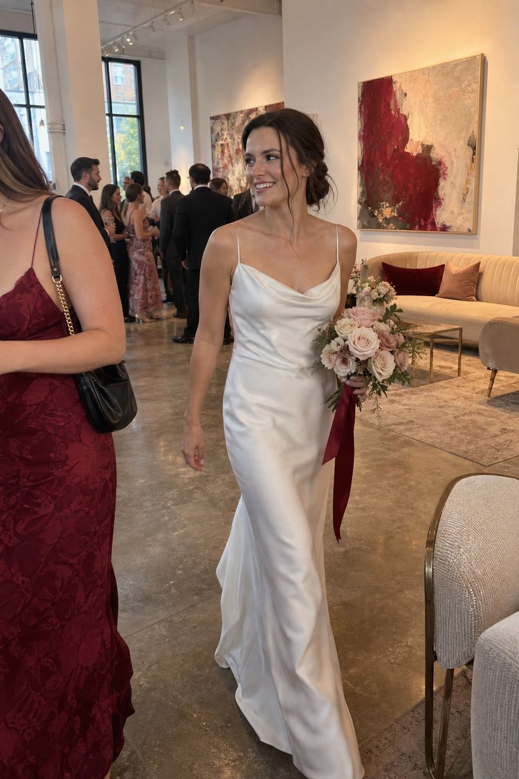 Bride walks through an intimate reception with a blush bouquet, crimson ribbon and champagne-toned accents.