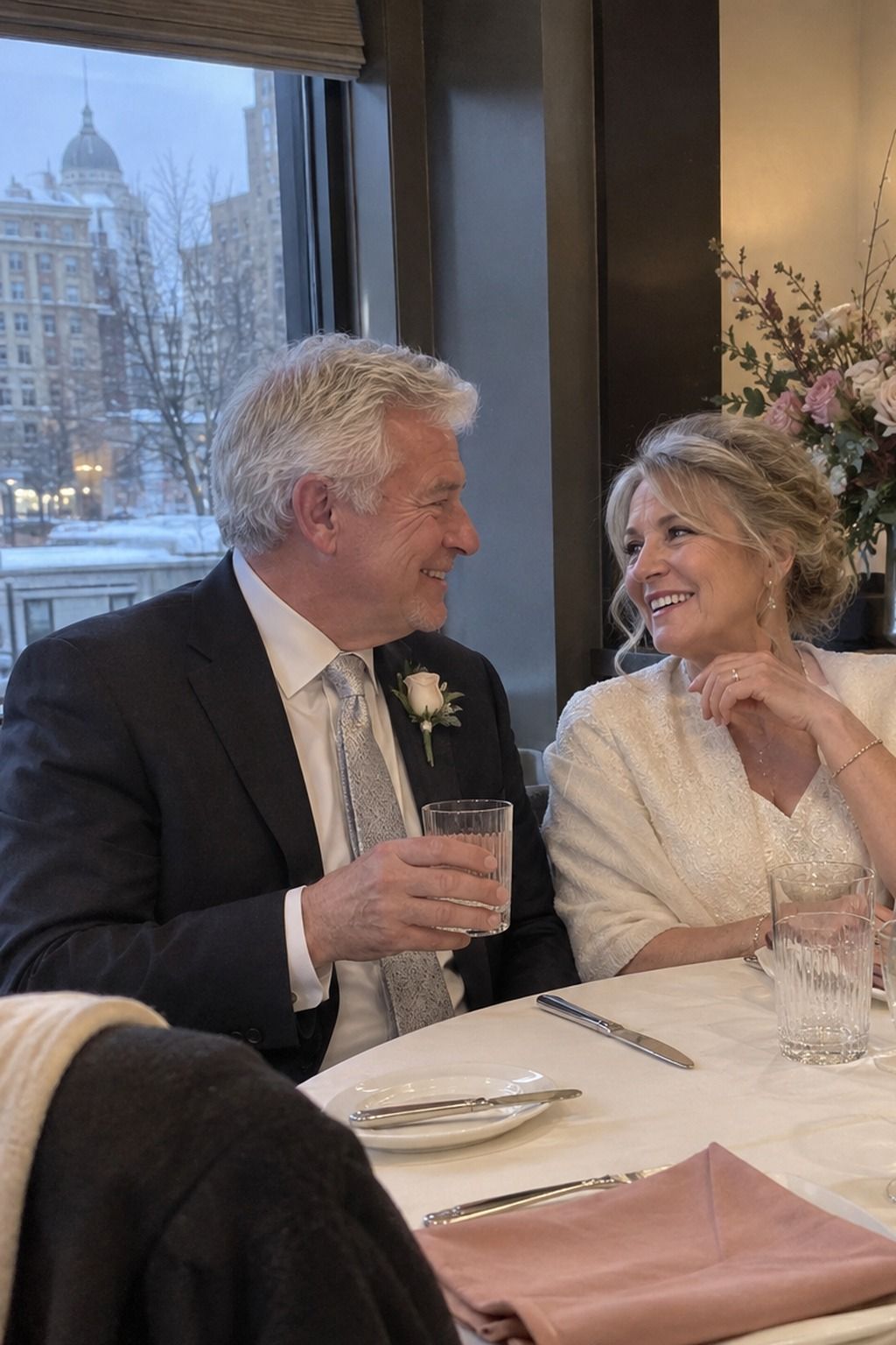 Older couple at a small winter reception with rose napkins, ivory linen and silver flatware.