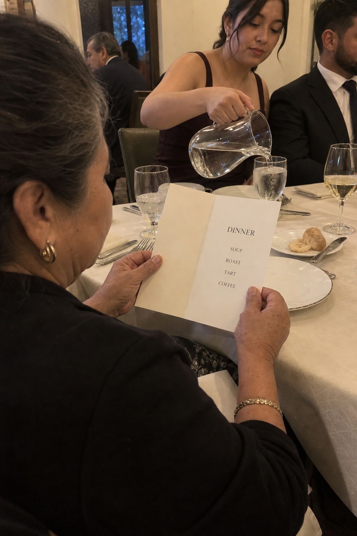 An older guest reads a letter-style dinner menu at an intimate February wedding.
