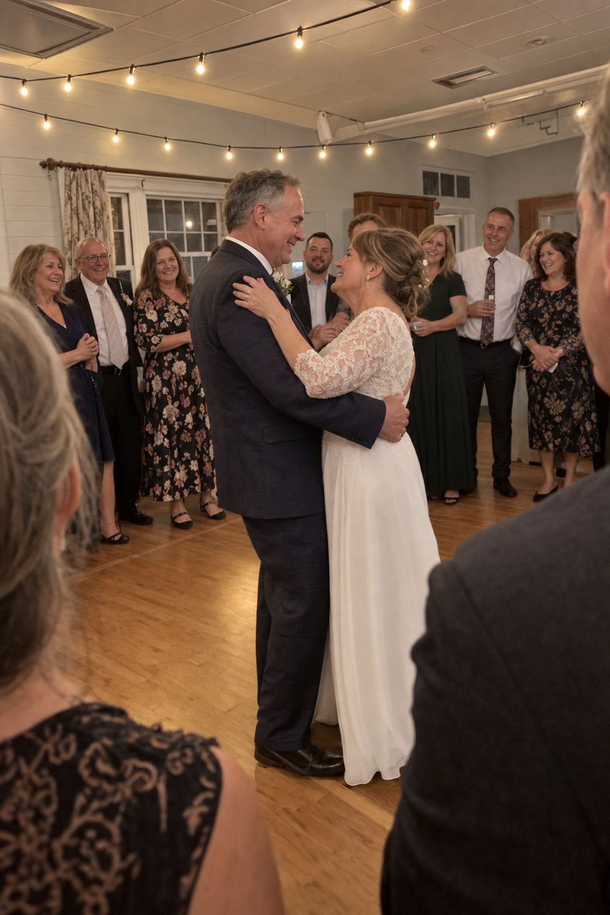 A mature couple shares a close first dance surrounded by family and friends.