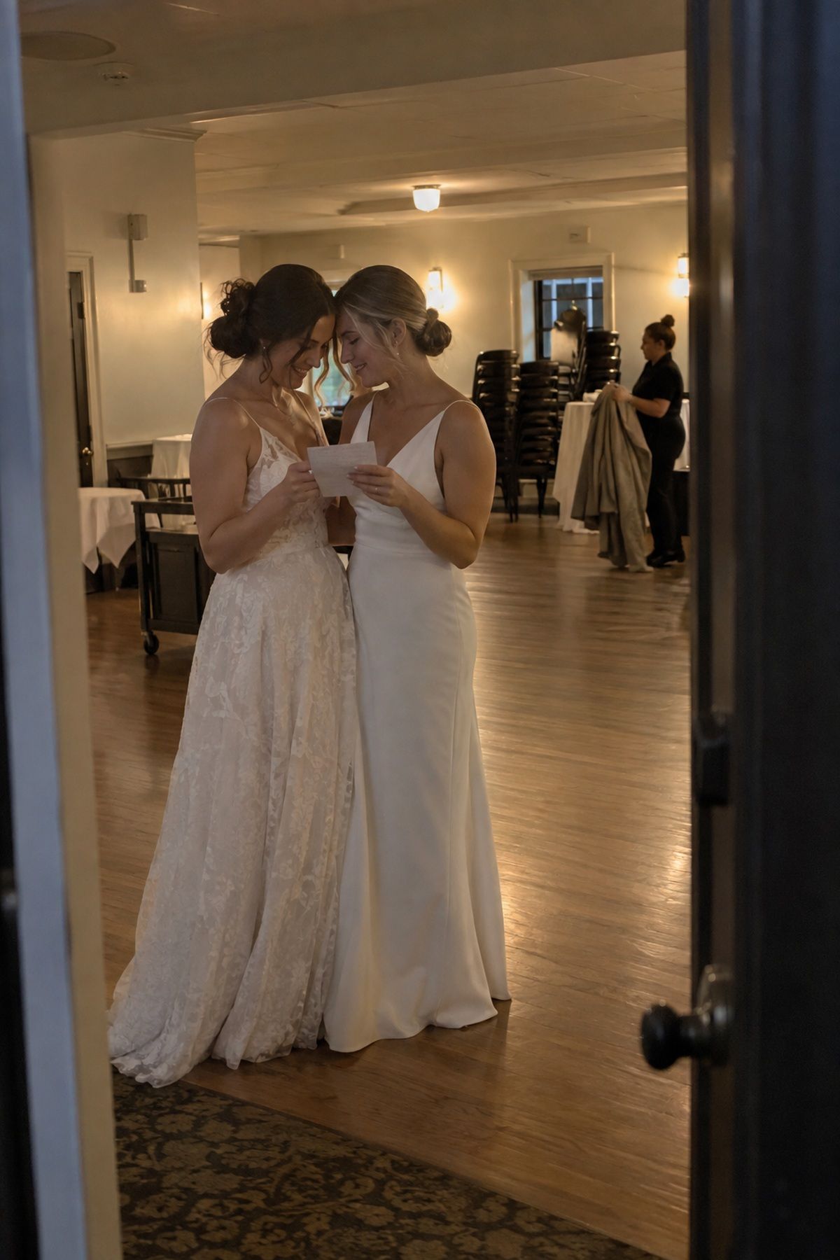 Two brides read a private letter together after their intimate winter wedding reception.