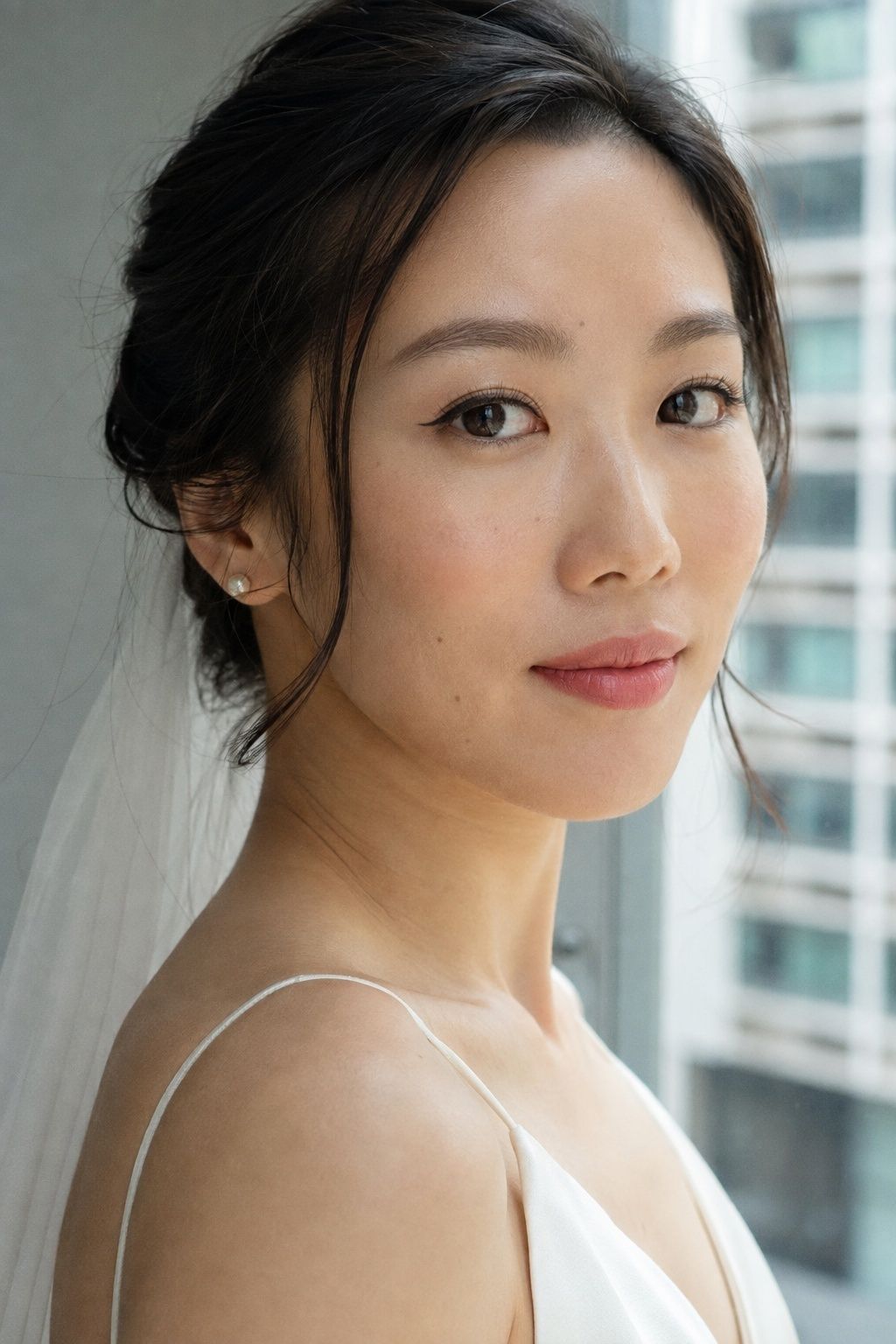 Soft short eyeliner wings and rose lips on a bride by a window.