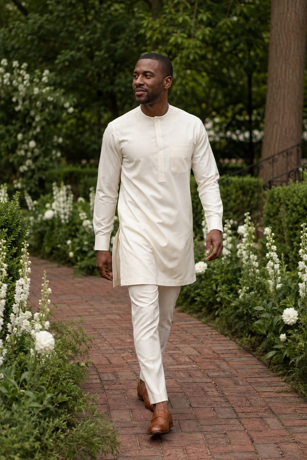 Man wearing an ivory longline tunic over slim trousers on a garden path.