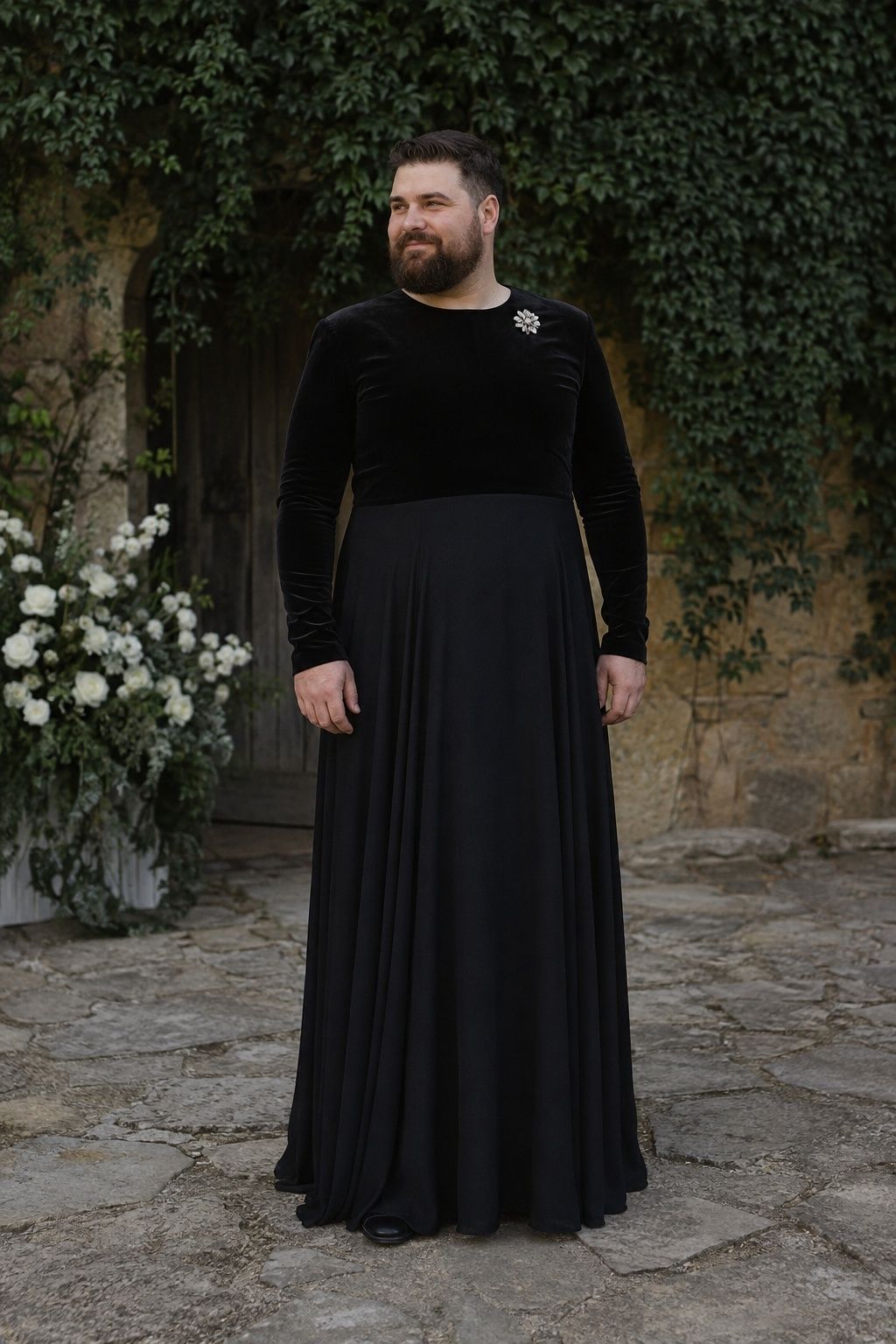 Man in a black velvet and crepe wedding gown with a silver brooch.