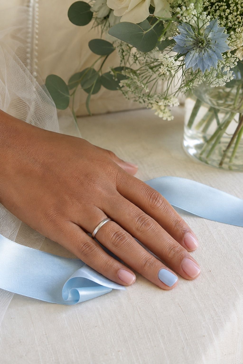 Powder blue ring-finger nail with sheer pink nails and a silver wedding band