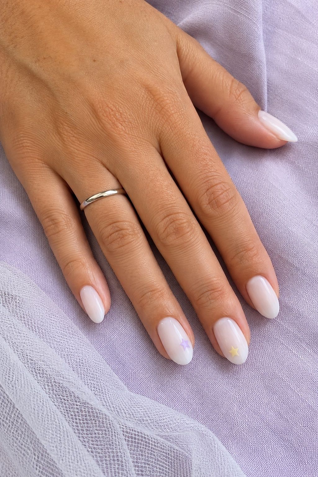 Tiny pastel stars on milky white almond wedding nails