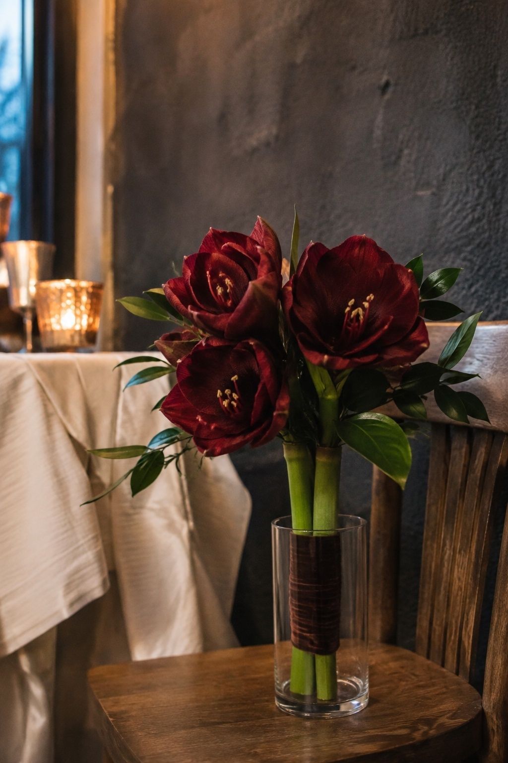 Deep burgundy amaryllis statement bouquet in an intimate candlelit dining room