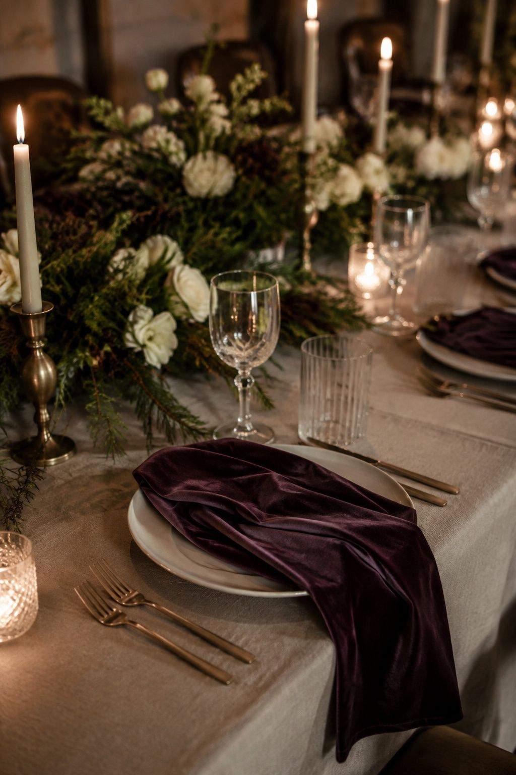 Deep plum velvet napkin at a candlelit winter wedding place setting